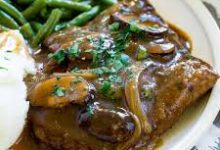 Plate of tender cube steak deer served with mashed potatoes and green beans.