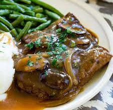 Plate of tender cube steak deer served with mashed potatoes and green beans.