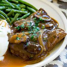 Plate of tender cube steak deer served with mashed potatoes and green beans.